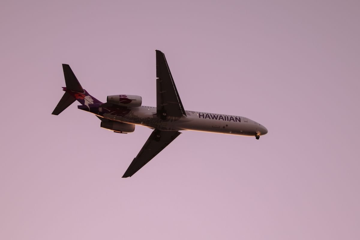 A Hawaiian Airlines jet in the sky at twilight over Kailua-Kona on Hawaii's Big Island