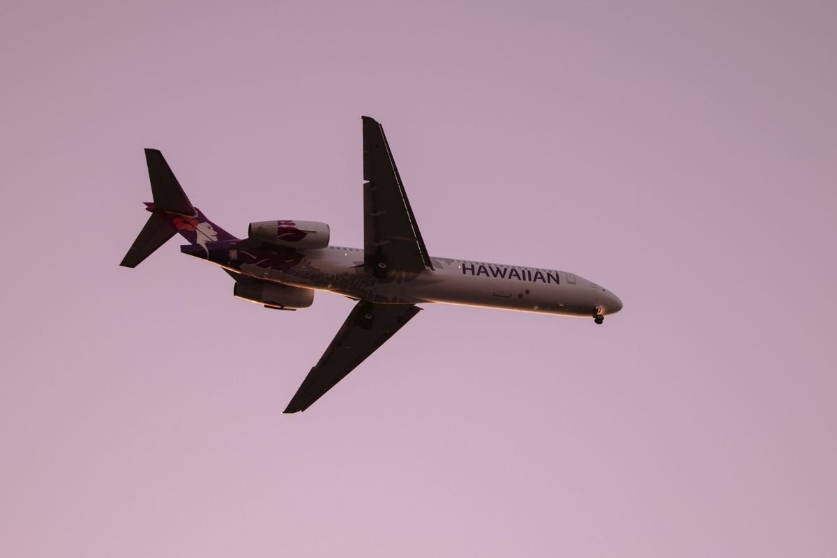Kona airport parking guide: a Hawaiian Airlines jet in the twilight sky over Kailua-Kona